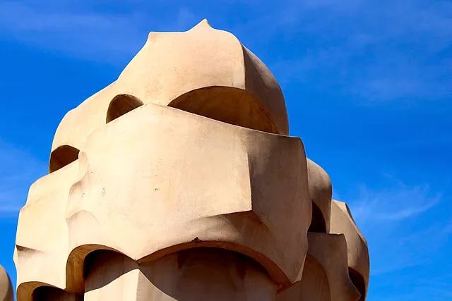 Stone chimney stacks on the roof of Casa Milà shaped like helmeted warriors, seen against a deep blue sky